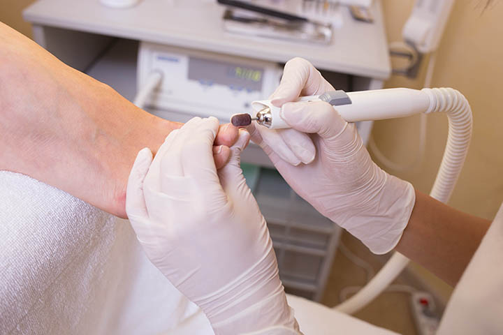 Мастер делает клиентке аппаратный педикюр Gehwol